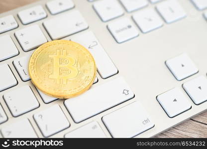 Golden bitcoin lying on a white keyboard . Golden bitcoin on a keyboard