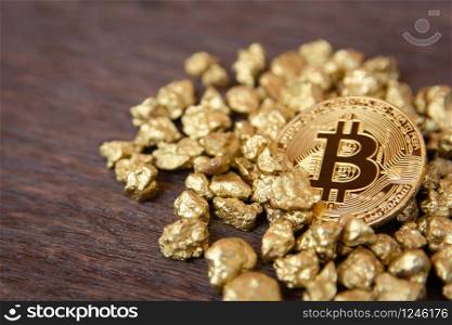 golden bitcoin on mound of gold nugget on dark wood background