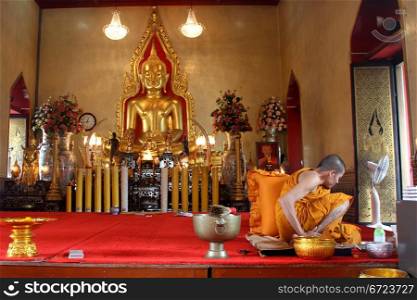 Golden Buddha and monk in buddhist temple in wat Traimit, Bangkok, Thailand