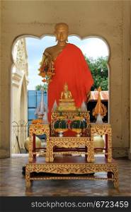 Golden Buddha in red robe near stupa Chedi Phra Pathom in Thailand