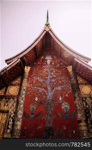 "Golden Buddism Mural art and mosaic wall "Tree of life" at Main hall of Wat Xieng thong, Luang Prabang, Laos"