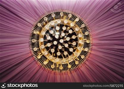 Golden chandelier with violet curtain, closeup view&#xA;