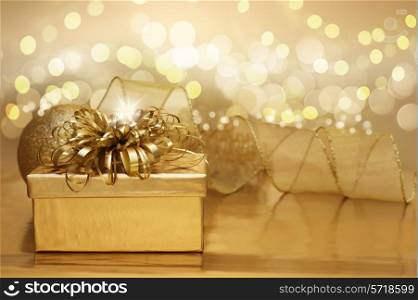 Golden Christmas background with a gift and bokeh lights