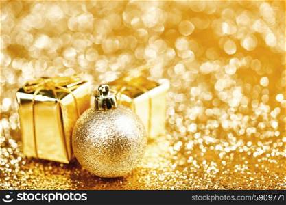 Golden Christmas ball and gifts on abstract glitter background