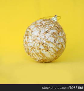 golden Christmas ball on a bright yellow background.