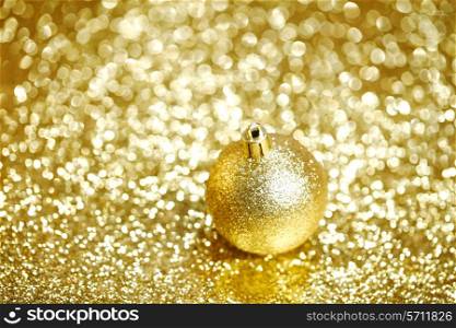 Golden christmas ball on shining glitter background close-up