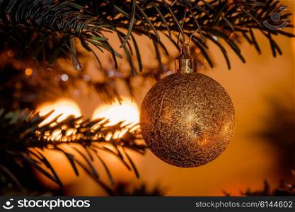 Golden Christmas ball with glittering lights hanging on the tree