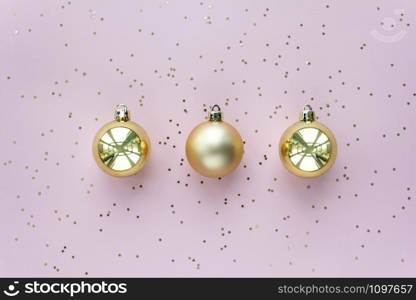 Golden christmas balls and stars on pastel pink background. Top view.. Golden christmas balls and stars on pastel pink background. Christmas sparkles composition.