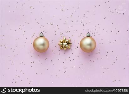 Golden christmas balls, golden bows and star confetti on pink pastel background top view. Flat lay composition for holidays. Golden christmas balls, golden bows and star confetti on pink pastel background top view. Flat lay composition for holidays.