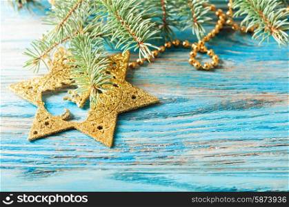 Golden Christmas decorations and fir branch on a blue wooden background