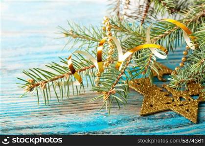 Golden Christmas decorations and fir branch on a blue wooden background