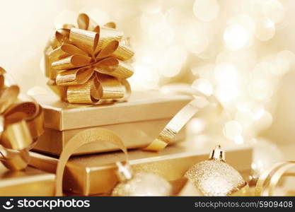 Golden christmas gift box and christmas balls on bokeh light background. Christmas gift and balls