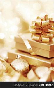 Golden christmas gift box and christmas balls on bokeh light background. Christmas gift and balls
