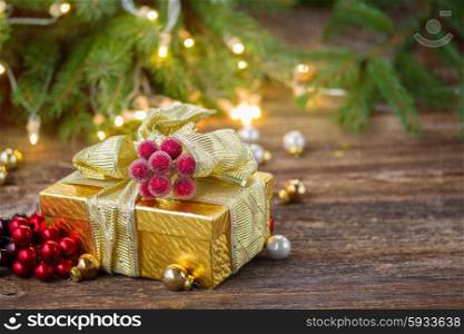 golden christmas gift box with lights in background on wooden table with copy space. christmas decorations with gift box