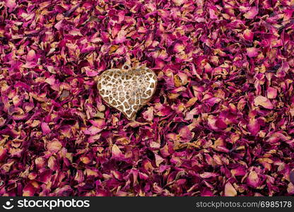 Golden color heart on dry rose petals background