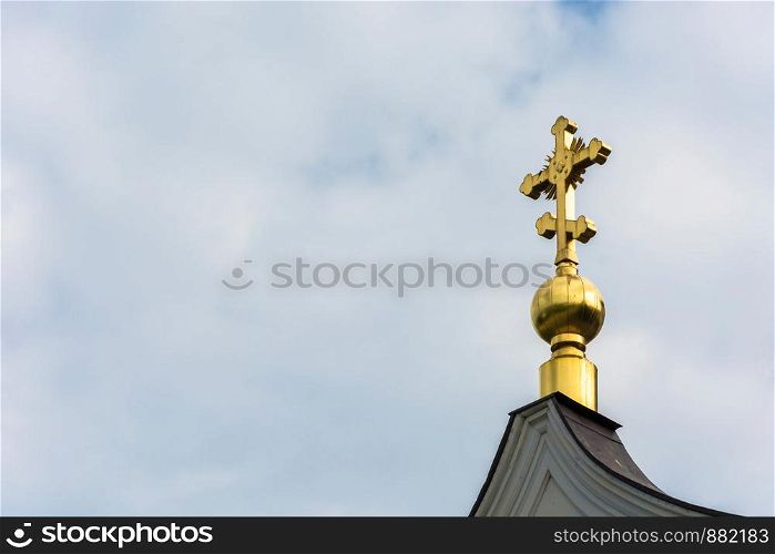 Golden cross on a small Golden dome on the background of cloudy sky.