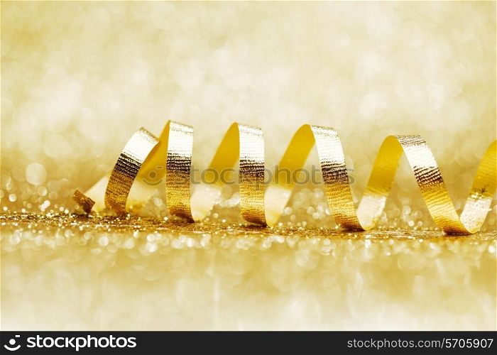 Golden curly ribbon decoration on glitter background close-up