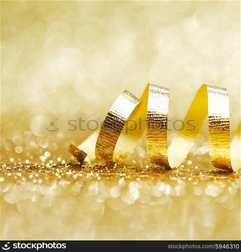 Golden curly ribbon decoration on glitter background close-up