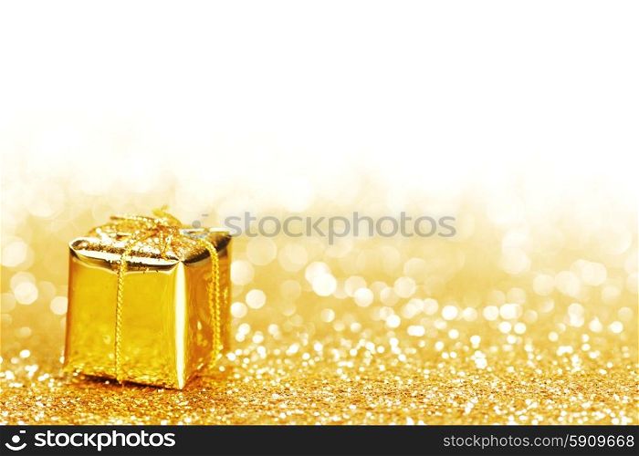 Golden decorative box with holiday gift on gold glitters background. Decorative gift box