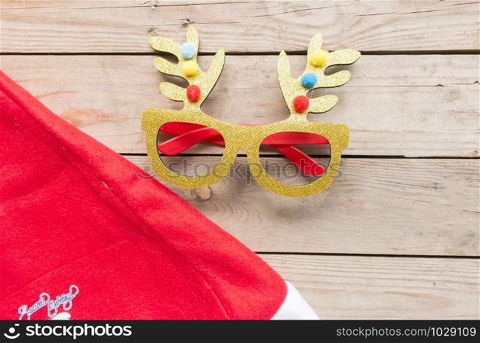 Golden deer eyes glasses with chrismas hat on woode background