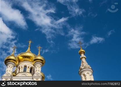 Golden domes of St. Alexander Nevsky Cathedral against a blue sky and white clouds.