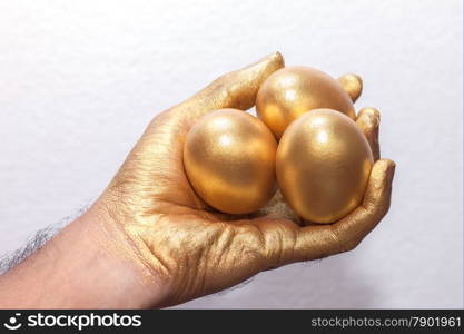 Golden egg on golden hand on white