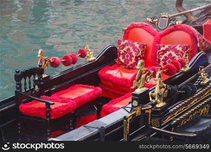 Golden figurines and red chairs on gondola near pier&#xA;