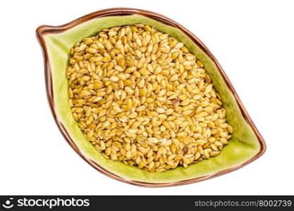 golden flax seeds on an isolated leaf shaped ceramic bowl, top view