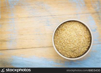 golden flaxseed meal - a ceramic bowl on grunge wood background with a copy space