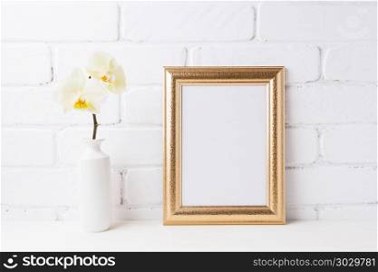 Golden frame mockup with soft yellow orchid in vase. Empty frame mock up for presentation artwork. Template framing for modern art.. Golden frame mockup with soft yellow orchid in vase