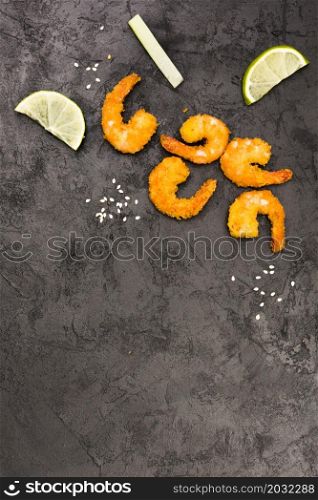 golden fried shrimps with sesame seeds lemon wedges rough black surface