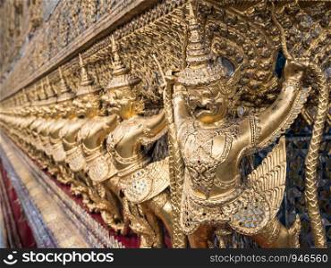 Golden garuda sculpture row around the church wall in the Thai temple.
