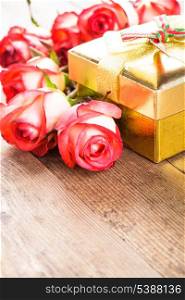 Golden gift box and bouquet of roses on the table