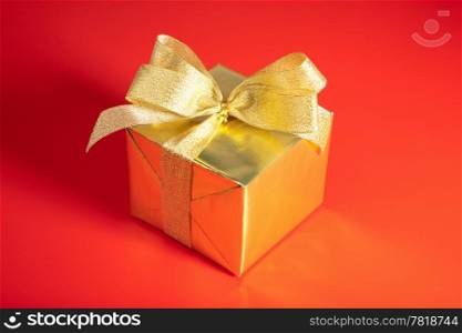 golden gift box with bow over red background