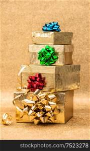 Golden gift boxes with ribbon bow on bright shiny background. Holidays decoration