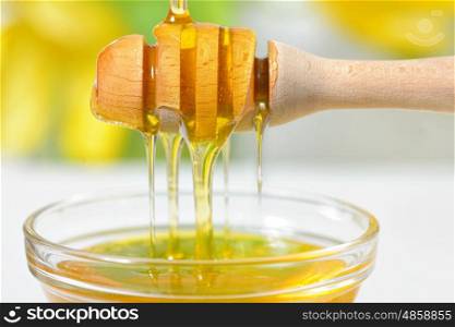 Golden honey dripping from dipper