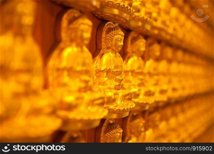 golden Image buddhas lined up along the wall of buddhist temple