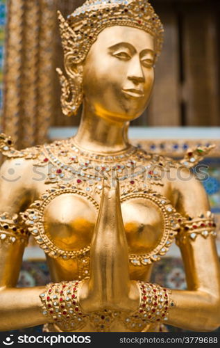 Golden Kinnari statue at Temple of Emerald Buddha (Wat Phra Kaew) in Grand Royal Palace. Half-bird, half-woman creature at south-east Asian Buddhist mythology. Bangkok, Thailand