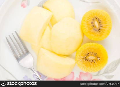 Golden kiwi fruit and sliced apple with fork in plate