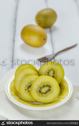 golden kiwi fruit and sliced . golden kiwi fruit and sliced on dish over white wooden background