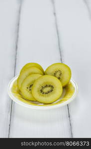 golden kiwi fruit and sliced . golden kiwi fruit and sliced on dish over white wooden background