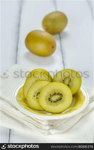 golden kiwi fruit and sliced . golden kiwi fruit and sliced on dish over white wooden background