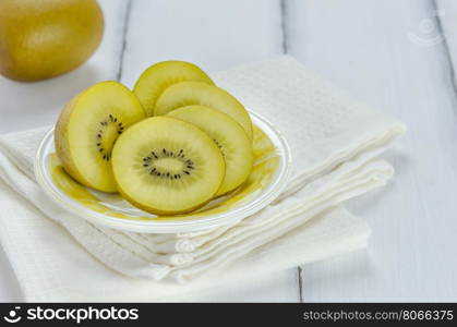 golden kiwi fruit and sliced . golden kiwi fruit and sliced on dish over white wooden background