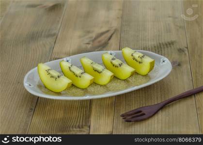 golden kiwi fruit and sliced . sliced of golden kiwi fruit on dish over wooden background
