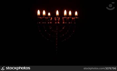 Golden Menorah with seven pin shines in the darkness