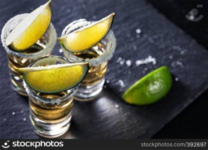 Golden Mexican Tequila on black background. Alcoholic cocktail. Mexican traditional drink. Golden Mexican Tequila on black background