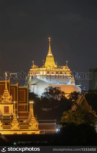 Golden Mountain pagoda, a buddhist temple or Wat Saket at night in Bangkok Downtown skyline, urban city, Thailand. Thai traditional architecture landscape background.
