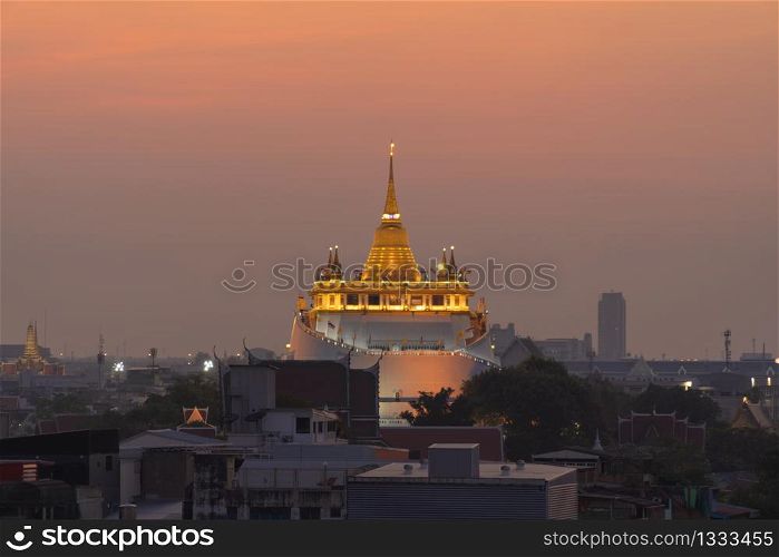 Golden Mountain pagoda, a buddhist temple or Wat Saket with the sun in Bangkok Downtown, urban city with sunset sky, Thailand. Thai architecture landscape background.