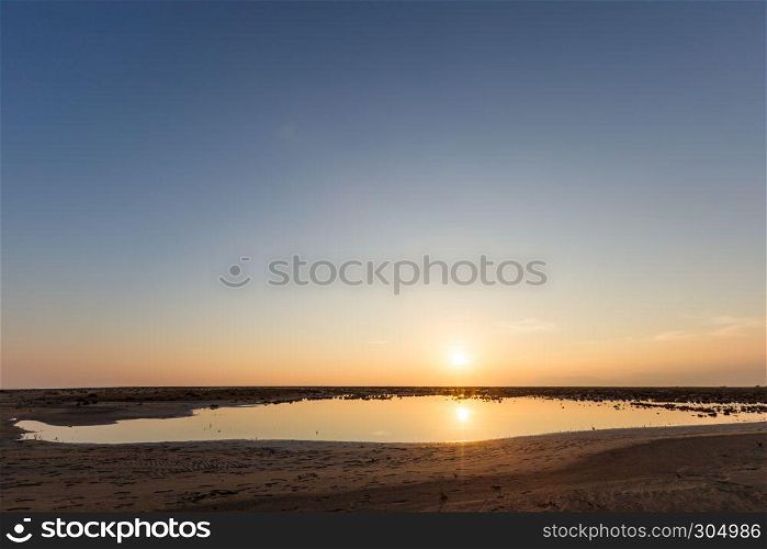 Golden natural small lake or pond sunset view of blue and orange sky landscape. Sunset or sunrise reflection in nature with sun in clouds above small water lake or pond. Golden natural small lake or pond sunset view