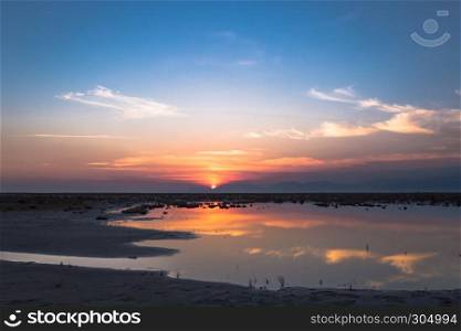 Golden natural small lake or pond sunset view of blue and orange sky landscape. Sunset or sunrise reflection in nature with sun in clouds above small water lake or pond. Golden natural small lake or pond sunset view